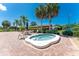 Community spa surrounded by brick pavers, palm trees, and seating under a clear blue sky at 525 Foxwood Blvd, Englewood, FL 34223