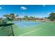 A tennis court is surrounded by tropical trees, with covered bench seating for relaxation and enjoying outdoor play at 525 Foxwood Blvd, Englewood, FL 34223