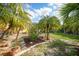 Well-maintained back yard with tropical landscaping featuring mulch, stone, and grassy areas at 621 Tarpon Way, Punta Gorda, FL 33950