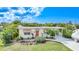 Well-maintained yellow house with red door, striped awnings and lush landscaping at 621 Tarpon Way, Punta Gorda, FL 33950