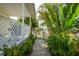 Lush side yard garden pathway leading to a gate, lined with vibrant greenery and tropical plants at 621 Tarpon Way, Punta Gorda, FL 33950