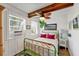 Charming bedroom featuring white wood-paneled walls, a decorative fan, and a green metal bed frame with colorful linens at 681 Olive St, Englewood, FL 34223