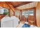 Rustic laundry room features wooden walls, a washer and dryer, plus a window for natural light and ventilation at 681 Olive St, Englewood, FL 34223