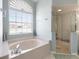 Bathroom featuring a soaking tub, glass enclosed shower, and a large window at 70 Sportsman Rd, Rotonda West, FL 33947