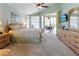 Bright main bedroom featuring a ceiling fan, large windows, and a wooden dresser with a wall-mounted TV at 70 Sportsman Rd, Rotonda West, FL 33947