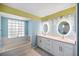 Bright bathroom with white vanity, double sinks, modern lighting, and separate tub at 803 Diane Cir, Englewood, FL 34223