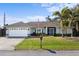 Well-maintained single-story home featuring a two-car garage, manicured lawn, and lush tropical landscaping at 803 Diane Cir, Englewood, FL 34223