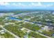 Wide aerial view of home and neighborhood with canal waterways, manicured lawns, and blue skies at 8205 Chico St, Port Charlotte, FL 33981