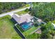 Birds eye view of the property with pool, well maintained lawn, storage shed, and mature trees at 8205 Chico St, Port Charlotte, FL 33981