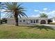 Welcoming single-story home with a charming arched garage door and lush green lawn at 84 Caddy Rd, Rotonda West, FL 33947