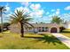 Charming single-story home with well-manicured lawn and mature palm trees at 84 Caddy Rd, Rotonda West, FL 33947