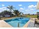 Sparkling in-ground pool surrounded by lush landscaping, mature trees, and a serene backyard view at 84 Caddy Rd, Rotonda West, FL 33947