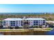 Multi-story building with colorful facade and balconies overlooks a serene lake and lush greenery at 8403 Placida Rd # 401, Placida, FL 33946