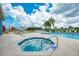 Community pool and spa with palm trees and chairs are set against a partly cloudy sky at 8431 Nighthawk Dr, Englewood, FL 34224