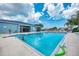 Wide angle shot of a bright blue community pool with a swimmer and large recreation building at 8431 Nighthawk Dr, Englewood, FL 34224