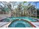 Sparkling in-ground pool and spa enclosed with an attached deck surrounded by lush greenery at 955 Morrison Ave, Englewood, FL 34223