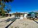 Charming single-story home featuring a covered patio, a picnic table, and beach-themed landscaping under a clear blue sky at 1115 Gulf Blvd, Englewood, FL 34223