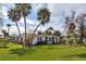 Charming single-story home with a lush lawn, mature palm trees, and a cozy outdoor patio area at 112 Gause Dr, Venice, FL 34293