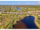 An aerial view of a lakeside home with mature landscaping, sunny skies and a large lake at 13241 Scrub Jay Ct, Port Charlotte, FL 33953