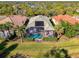 Aerial view of a backyard pool with screened enclosure and solar panel on a large lush lot at 13241 Scrub Jay Ct, Port Charlotte, FL 33953