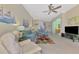Well-lit living room featuring tile floors, sofas, ceiling fan, and access to other rooms in the home at 13241 Scrub Jay Ct, Port Charlotte, FL 33953