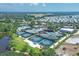 An aerial view shows the multiple tennis and pickleball courts surrounded by lush landscaping and a view of the ocean at 15 Boca Royale Blvd, Englewood, FL 34223