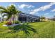 Lush green backyard with tropical landscaping, palm trees, and a screened-in lanai at 170 Long Meadow Ln, Rotonda West, FL 33947