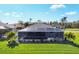 Wide backyard view of a screened-in pool and patio area surrounded by tropical landscaping at 170 Long Meadow Ln, Rotonda West, FL 33947