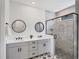 Modern bathroom with double vanity, dual mirrors, and a glass-enclosed shower at 18575 Midsummer Pl, Venice, FL 34293