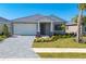 Inviting single-story home featuring a covered porch, well-manicured lawn, and a paver driveway, offering a warm welcome at 18575 Midsummer Pl, Venice, FL 34293