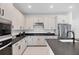 Sleek kitchen with white cabinetry, black countertops, stainless steel appliances, and modern fixtures, creating a stylish cooking space at 18575 Midsummer Pl, Venice, FL 34293