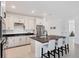 Stylish kitchen boasting a large island with bar stools, white cabinets, and stainless steel appliances, ideal for culinary enthusiasts at 18575 Midsummer Pl, Venice, FL 34293
