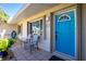 Inviting front porch with seating, vibrant blue door, and a well-kept exterior in a cozy neighborhood at 1910 Greenlawn Dr, Englewood, FL 34223