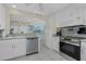 Kitchen with stainless steel appliances, white cabinets, and a breakfast bar at 1910 Greenlawn Dr, Englewood, FL 34223