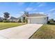 Wide concrete driveway leads to a light gray single-Gathering home with a well-kept lawn and landscaping at 23 Fairway Rd, Rotonda West, FL 33947