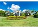 Landscaped entrance to a clubhouse with lush greenery and colorful flower beds at 26636 Irwin Dr, Englewood, FL 34223