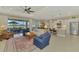 Open-concept living room featuring neutral tones, tile floors, ceiling fan and sliding glass doors to lanai at 26636 Irwin Dr, Englewood, FL 34223