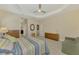 Spacious bedroom with a ceiling fan, striped bedding, comfortable armchair, and neutral decor for relaxation at 26636 Irwin Dr, Englewood, FL 34223