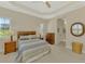 Comfortable bedroom with a ceiling fan, striped bedding, wooden furniture, and natural light from the windows at 26636 Irwin Dr, Englewood, FL 34223