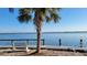 Picturesque water view featuring a pier, park bench, palm trees, and a life ring for safety by the shore at 5055 N Beach Rd # 203, Englewood, FL 34223