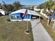 Charming blue home with an American flag, covered carport, and well-maintained landscaping at 6347 Oriole Blvd, Englewood, FL 34224