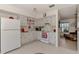 Bright kitchen with white appliances and cabinetry, neutral tile flooring and view to adjacent living area at 6522 Coliseum Blvd, Port Charlotte, FL 33981