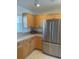 Bright kitchen featuring a stainless steel refrigerator, natural wood cabinets, and speckled counters at 8937 Bantry Bay Blvd, Englewood, FL 34224