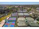 Aerial view of multiple fenced tennis courts with a lake and lush trees nearby at 9 Fairway Dr, Englewood, FL 34223