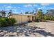 Exterior view of a light yellow home with a gravel driveway and vibrant foliage at 1320 Bayshore Dr, Englewood, FL 34223