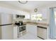 Bright kitchen with white cabinetry, stainless steel appliances, and a window providing natural light at 18970 Mcgrath Cir, Port Charlotte, FL 33948