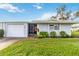 Charming one-story home featuring an attached garage, screen door entry, and lush, well-maintained lawn and landscaping at 3220 Southfield Ln # 810, Sarasota, FL 34239