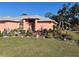 Attractive coral home with a well-manicured lawn, lush landscaping, and a decorative glass front door at 501 Cobalt Rd, Englewood, FL 34223