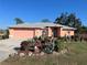 Charming coral home showcasing a beautiful front yard with lush, colorful landscaping and a gray roof at 501 Cobalt Rd, Englewood, FL 34223