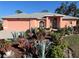 Inviting coral home with lush landscaping, a gray roof, a two-car garage and a decorative glass front door at 501 Cobalt Rd, Englewood, FL 34223